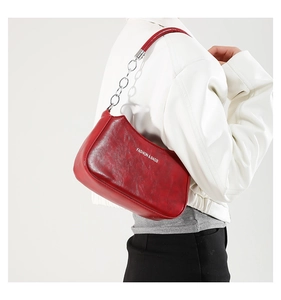 Close-up of vintage red faux leather crescent bag with chain strap and printed text