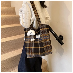 Detail of checkered knit tote bag with plush cloud charm and white brand label