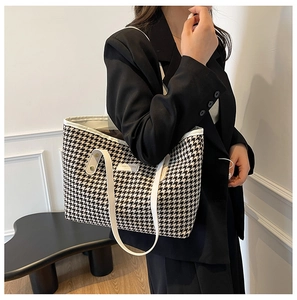 Detailed shoulder view of a large houndstooth canvas tote bag with white leather handles