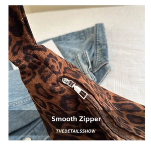 Close-up of the smooth silver metal zipper and soft leopard print suede fabric details