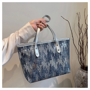 Detail of blue denim tote bag featuring wavy silver sequins and metallic silver handles