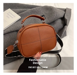 Close-up of brown litchi pattern leather handbag with cross-stitching and wide strap