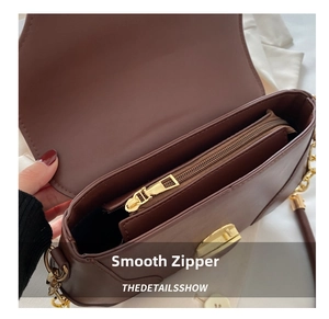 Detail view of smooth golden zipper and organized interior of the brown leather bag