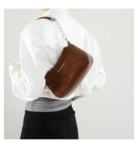 Close-up of brown crescent bag with oily leather finish and silver chain strap