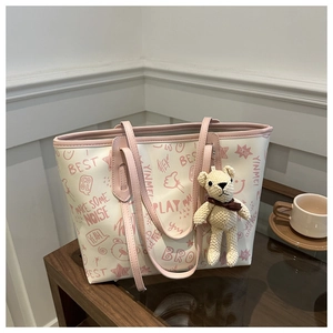 Detail of white tote bag with pink graffiti prints and cute knitted bear charm pendant