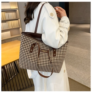 Close-up of houndstooth weave texture and leather brand label on the vintage tote bag