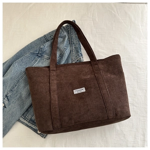 Detail of dark brown corduroy tote bag showing ribbed texture and fashion label