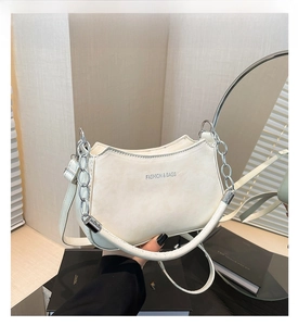 Detail of creamy white leather handbag featuring a chunky silver chain and silver embossing