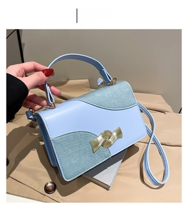 Détail du sac à main bleu en cuir croco avec boucle dorée et bandoulière assortie