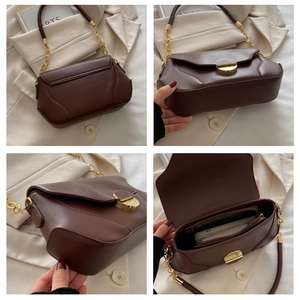 Detail view of brown leather bag with gold cylinder buckle and chain strap