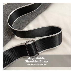 Close-up of adjustable woven black and white shoulder strap with silver metal buckle