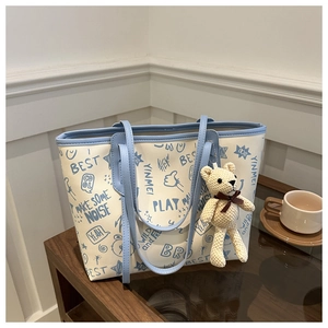 Detail of cute bear charm and blue graffiti letters on cream oversized tote bag