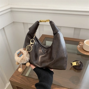 Sac dumpling minimaliste en cuir marron foncé avec détails dorés et décoration peluche