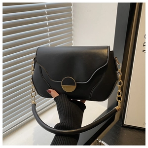 Détail d'un sac bandoulière noir avec un fermoir doré demi-cercle et une chaîne