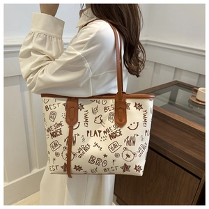 Detail of white tote bag with brown straps featuring vintage bear and graffiti prints
