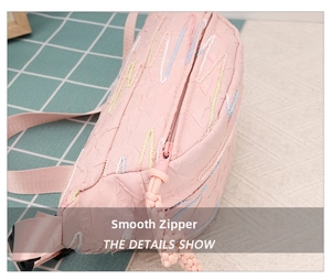 Close-up of pink corduroy bag with colorful wavy stitching and smooth zipper detail