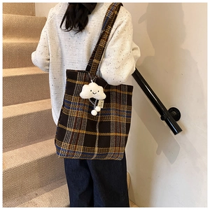 Detail of plaid tote bag with classic tweed pattern and cute white plush cloud charm