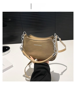 Detail view of khaki shoulder bag with silver chain and white fashion text logo