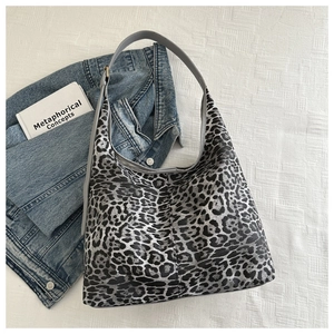 Detail view of large leopard print tote bag styled with denim jacket and books