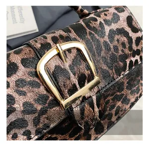 Close-up of elegant gold rectangular metal buckle on leopard print crossbody bag