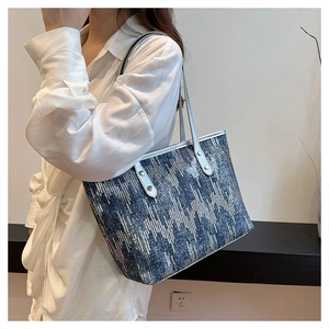 Detail of blue denim tote bag featuring silver sequins and metallic rivet handles