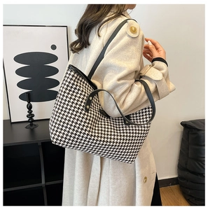 Detailed view of houndstooth tote bag with leather straps on a fashion model