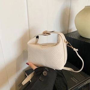 Sac à main beige tissé avec texture à carreaux et boucle dorée dans un décor chic