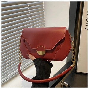 Détail d'un sac bandoulière bordeaux en cuir avec boucle dorée et chaîne stylée