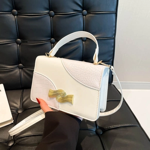 Sac à main blanc à texture crocodile et fermoir ondulé doré sur fauteuil en cuir noir