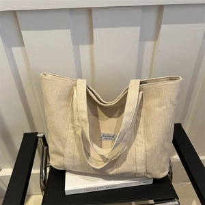 Minimalist beige corduroy tote bag with Fashion Instinct label on a black chair