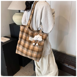 Detail of vintage checkered tote bag with a white plush cloud charm and logo patch