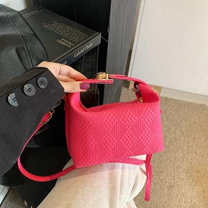 Sac à bandoulière rose texturé à rayures avec boucle dorée tenu à la main pour un look chic