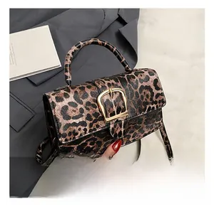 Detailed view of leopard print crossbody bag with large gold metallic decorative buckle