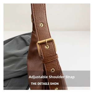 Detail of adjustable brown pebbled leather shoulder strap with golden buckle hardware