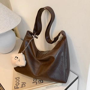 Large brown faux leather shoulder bag with wide strap and plush bear charm