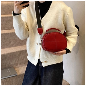 Detail of red litchi grain shoulder bag with wide black and white woven strap