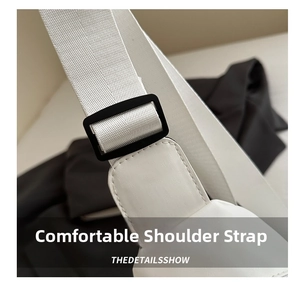 Close-up of adjustable nylon shoulder strap and black buckle on white crossbody bag