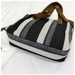 Detail of woven striped canvas tote bag showing the textured black white and grey fabric