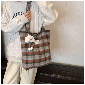 Close-up of a vintage plaid canvas tote bag featuring a cute white cloud plush charm