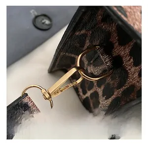 Macro detail of leopard print shoulder bag featuring a polished gold-tone metal clasp