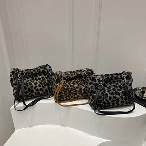 Three leopard print plush tote bags with chain straps displayed on a white tiered stand