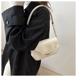 Détail du sac à bandoulière en cuir blanc avec boucle dorée ronde et chaîne dorée