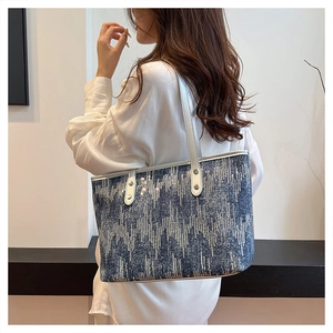 Detail of blue geometric sequined tote bag with silver leather shoulder straps and rivets