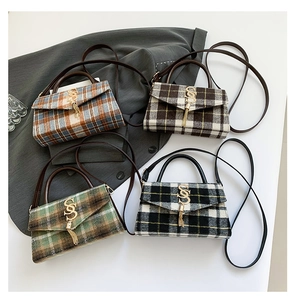 Detail of tweed crossbody bag featuring metallic S-buckle and elegant tassel charms
