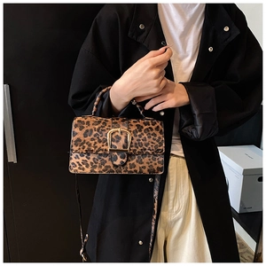 Detail of trendy leopard print handbag with golden buckle and crossbody strap on a model