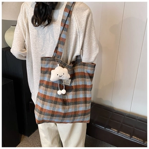 Detail of plaid canvas tote bag featuring a cute white cloud plush pendant accessory