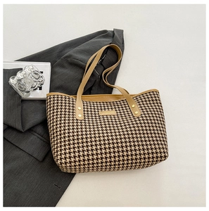 Detail of classic houndstooth weave patterns on a large tote bag with leather trim