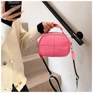 Detail of fuchsia lychee leather crossbody bag with striped wide shoulder strap