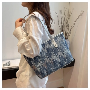 Detail of blue denim tote bag with silver sequin stripes and grey leather shoulder strap