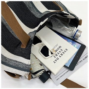 Detail view of large striped tote bag capacity with everyday items and zipper closure